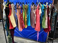 Photo of assorted women's sleeveless tank tops and shirts hanging on a clothing rack, showing a variety of colors and styles.