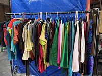 Rack of assorted shirts in various colors, styles, and patterns hanging on rack.