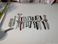 Photo showing a collection of wristwatches and watch bands laid out on a table. Various styles and colors of watches and bands are clearly visible.
