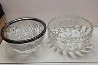 Photo of two glass bowls, one with metal rim and star cut pattern, other with floral pattern and zigzag rim