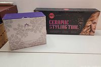 Two boxed items on a white table: PVT Ceramic Styling Tool and Sutra Flat Iron Holder