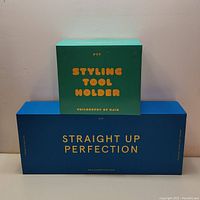 Two boxes stacked, blue box labeled 'Straight Up Perfection' and green box labeled 'Styling Tool Holder'