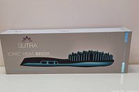 Front box view of the blue Sutra Ionic Heat Brush showing product name and brush image.