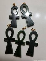 Five jade ankh pendants displayed on flat surface showing color and shape variations