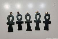 Five jade ankh pendants shown from front on a white surface, metal bails visible on each pendant.