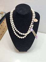 Front view of cultured pearl necklace displayed on black bust showing the full necklace strand with pearls and silver clasp.