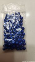 Clear plastic bag containing approximately 100 round blue lapis lazuli beads.