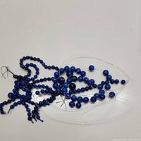 Top view of multiple strings of lapis lazuli beads in small to medium sizes laid out on a white surface showing their shape and color