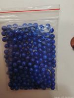 Bag containing numerous small round lapis lazuli beads with drilled holes.