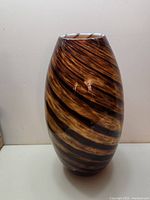 Front view of the orange and black swirl patterned glass vase showing the elongated oval shape and narrow opening.