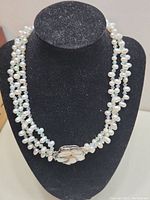 Full view of the double strand pearl necklace displayed on a black stand to show overall design and clasp placement.