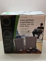 Photo of the product packaging showing two Centrios wireless panel speakers, remote, and cables.