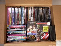 Box view showing assorted DVD cases packed side-by-side with visible spines showing movie titles.