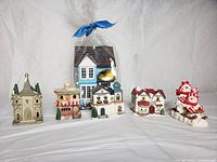 All Christmas village houses and snowmen figurines arranged on white background showing details and color variety.