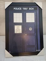 Full view of framed Doctor Who TARDIS poster with protective corner guards visible.