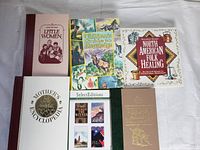 Six hardcover books arranged on a flat surface including 'Little Women', 'Children's Guide to Knowledge', 'North American Folk Healing', 'Mother's Encyclopedia', Select Editions, and one brown hardcover with title partially visible.