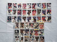 Photo shows spread-out hockey cards arranged on white surface, displaying front images of players in various team uniforms and action poses.