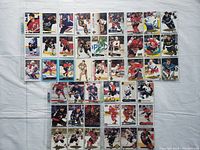 Top-down view of 45 hockey cards laid out on white fabric, showing a variety of teams and player action shots.