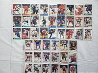 Photo showing 36 hockey cards arranged in rows on a white background with players in various NHL team jerseys.