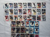 Photo showing a front view of 27 hockey cards arranged in rows inside a plastic sleeve, featuring players in various hockey uniforms representing multiple teams, with differing card designs and colorful borders.
