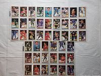 Photo showing 35 hockey cards arranged in rows on a white background. Cards are stored in plastic sleeves and show various players on different teams.