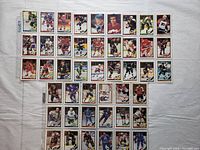 Photo shows 45 hockey cards arranged in 5 rows and 9 columns on a light surface. All cards are enclosed in plastic sleeves. Each card features a hockey player in uniform, posed or in action on the ice.