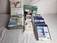 Photo showing a collection of bedroom linens including bedbug solution mattress cover, Stevens bedding set, folded fitted sheet and pillow encasings.