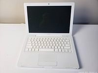Front view of open white 2007 Apple MacBook showing keyboard, trackpad and screen.