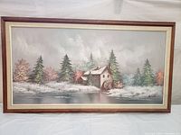 Frontal view of the signed oil painting showing the full winter landscape with snow, watermill, trees, and river, framed with a brown and cream border.