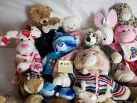 Photo showing assortment of different stuffed animals including bears, dog, rabbits, lion, and monkey character.