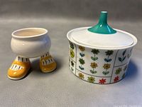 Side view of the Carlton Ware Walking Egg egg cup and the Rosenthal Emilio Pucci covered sugar bowl with floral pattern and turquoise lid finial.