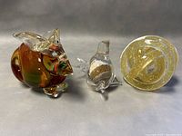 Photo showing the three Murano glass items: Sommerso bunny, sand glass bird, glass knot paperweight with gold flecks.