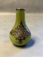 Close-up view of the 3.5 inch green glass miniature bud vase with silver overlay, showing decorative silver filigree detail and minor chip at rim.