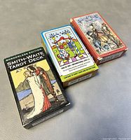 Three boxes of tarot cards including Smith-Waite Borderless Edition and two artistic fantasy tarot decks