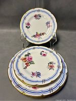 Stacked 8 plates showing floral patterns, blue rim and gold trim