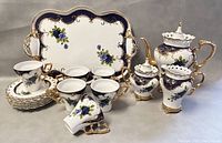 View showing full tea set including tray, teacups, saucers, teapot, sugar bowl, creamer with detailed colors and patterns.
