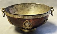 Front view of copper cauldron showing two dragon ring handles and Greek key border