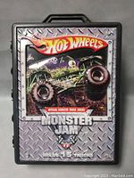 Front of plastic carrying case showing Hot Wheels Monster Jam branding with large monster truck image and text 'Holds 15 Trucks'
