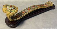 Frontal view of gilt cloisonné enamel Ruyi sceptre resting on wood stand