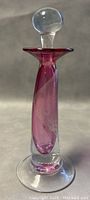 Front view of the blown art glass perfume bottle showing its shape, pink spiral design, and clear rounded stopper.
