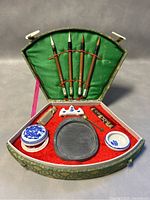 Full set overview inside open fan-shaped box showing brushes, ink stone, ink sticks, porcelain containers and accessories.