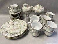 Full set of vintage Nippon porcelain tea set including sugar bowl, creamer, cups, saucers, and luncheon plates arranged on a table.