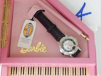 Barbie wristwatch with black leather band resting in pink presentation/display box with gold Barbie logo and a Certificate of Authenticity card.