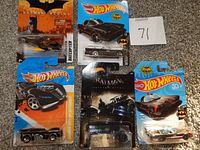 Photo shows five Hot Wheels Batman-related vehicles in original packaging: Batcopter from Batman Begins, multiple Batmobiles including Arkham Knight and 80 Years DC collection.
