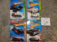 Four new Hot Wheels die cast cars in original packaging: Chain Reaction (blue futuristic car), Volkswagen Beetle (silver), Batmobile (black with orange details), and a classic black and silver car with red details.
