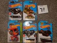 Lot of 5 Hot Wheels die cast cars in original packaging arranged on table with a lot number card.
