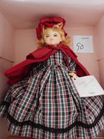 Madame Alexander Molly doll in box, wearing plaid dress and red cape with bonnet, shows doll condition and original tag.
