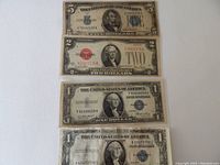 Front view of four silver certificate bills including $5, $2, and two $1 bills.