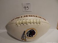 White football with Redskins logo and wordmark, close-up of lacing and front side