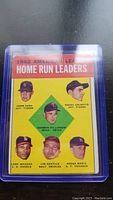 Photo of 1962 Topps American League Home Run Leaders baseball card with portraits of Harmon Killebrew, Roger Maris, and other players, in protective sleeve